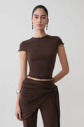 Woman wearing a brown high neck top with piping detail.