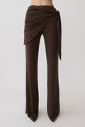 Woman wearing brown straight leg pants with waist wrap.