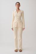 Woman wearing a white ribbed long sleeve longline top with ribbed flared pants.