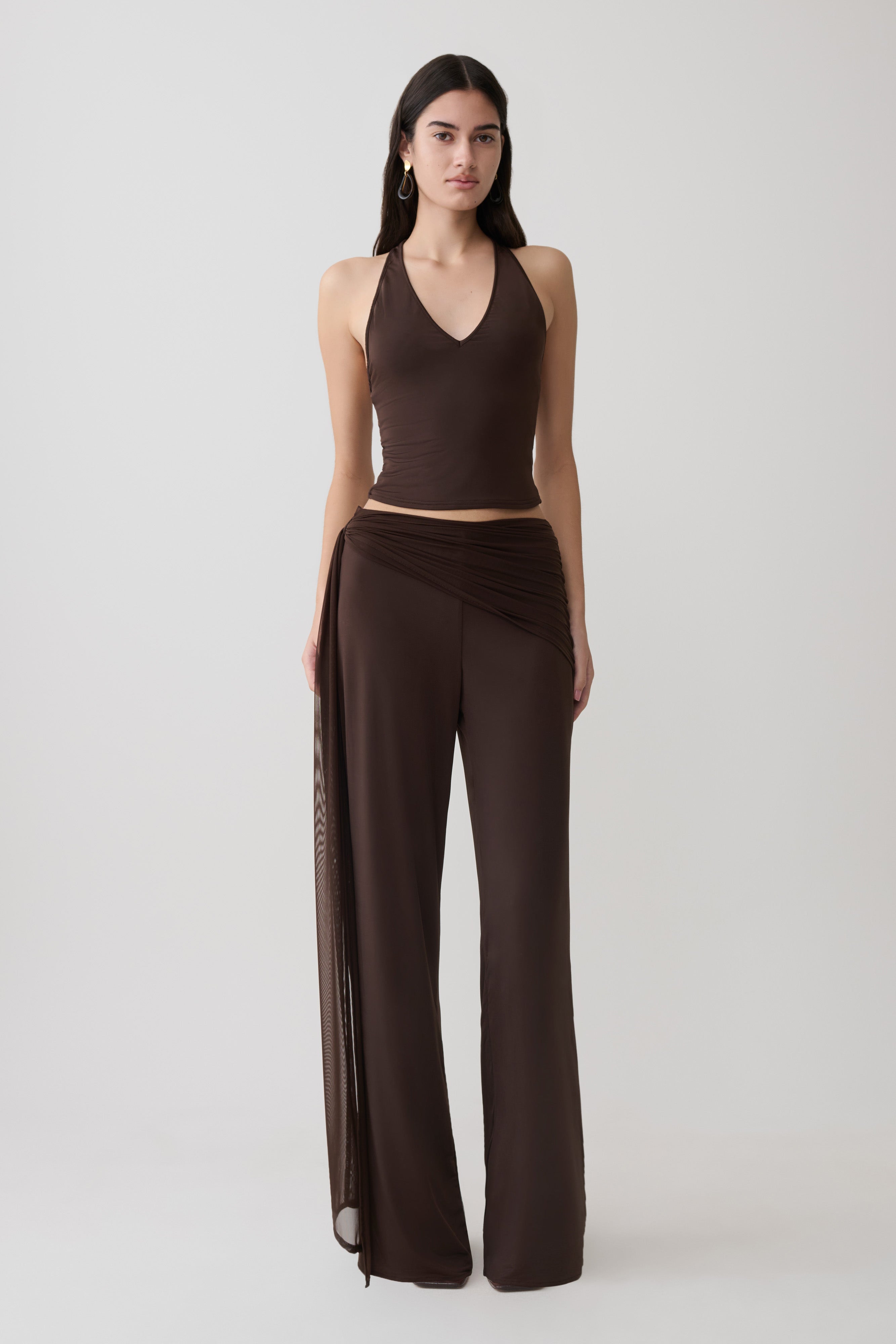 Woman wearing a brown slinky and mesh top with slinky gathered wide leg pants.