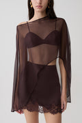Woman wearing brown bralette with chiffon cape with matching lace and satin mini skirt.