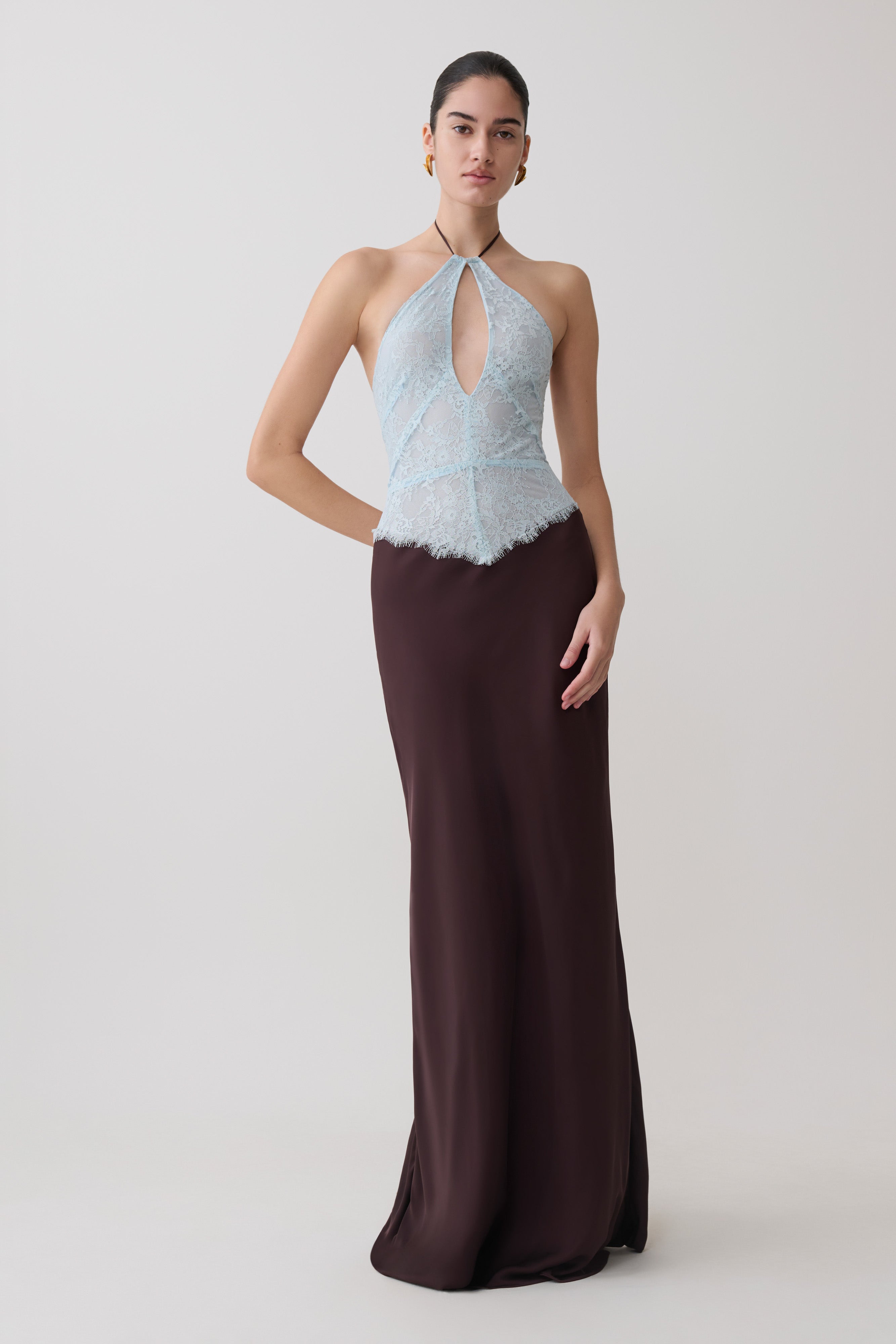 Woman wearing a light blue and dark brown lace and satin halter maxi dress.