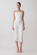 Woman wearing a white embroidery strapless denim top and white flower embroidery denim capris.
