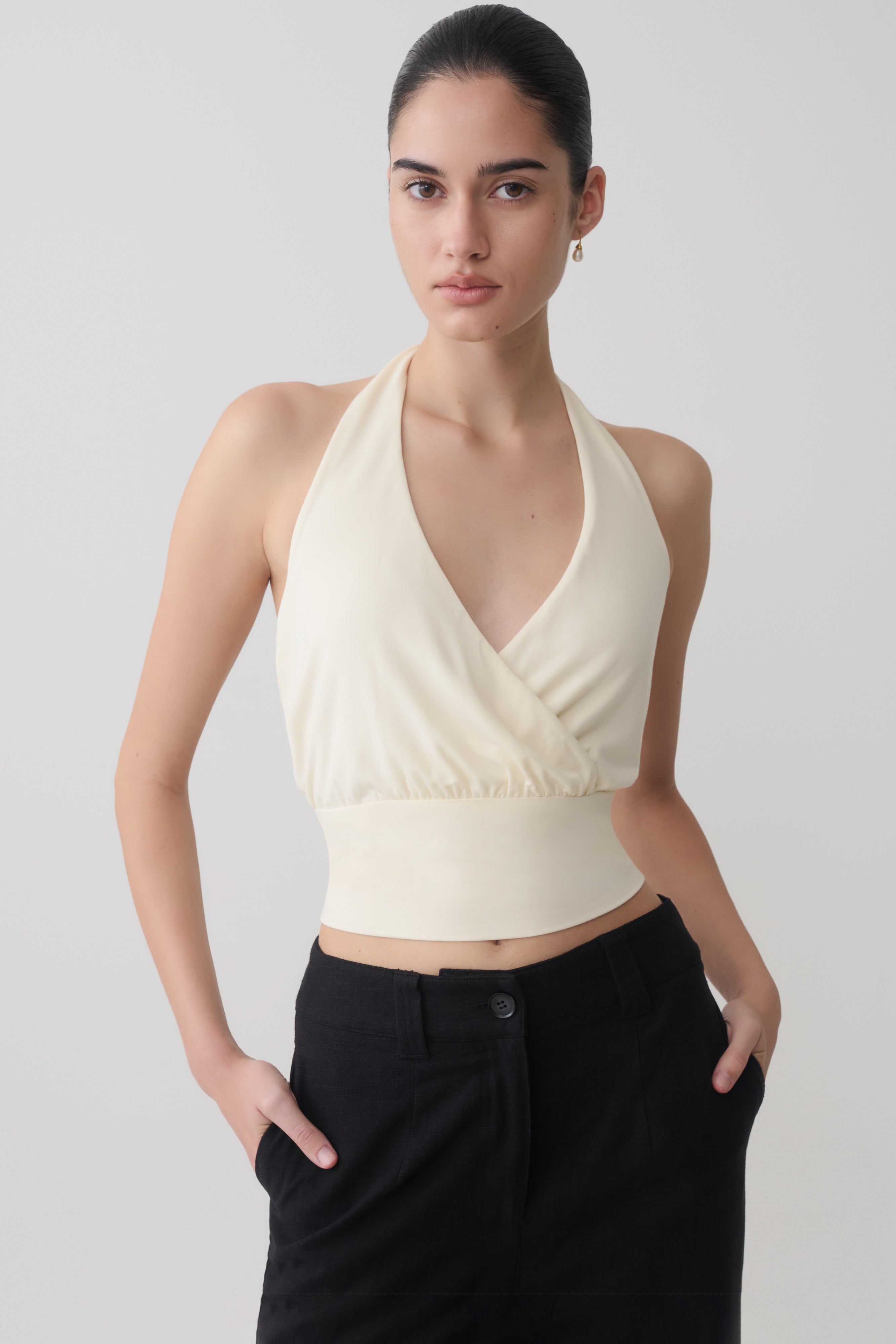 Woman wearing a white draped halter top.