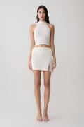 Woman wearing a white halter backless knit top with matching skirt.