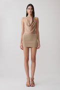 Woman wearing a gold lurex cowl neck top with matching mini skirt.