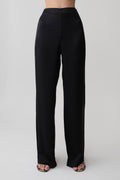 Woman wearing black straight leg satin pants.