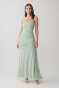 Woman wearing a light green strapless ruched mesh maxi dress.
