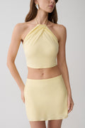 Woman wearing a light yellow halter top and matching mini skirt. 