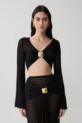 Woman wearing a black crochet long sleeve cropped top.